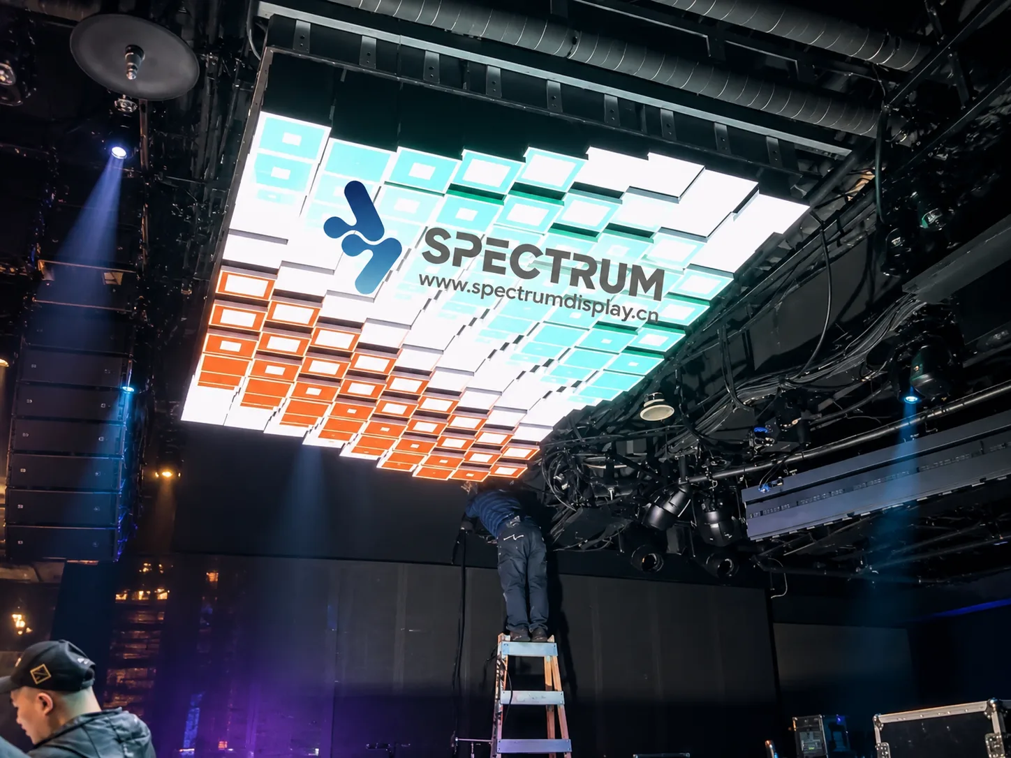 Spectrum Display SPKI ceiling-mounted mechanical LED wall installation - engineer surveying and servicing the kinetic screen structure before commissioning