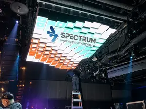 Spectrum Display SPKI ceiling-mounted mechanical LED wall installation - engineer surveying and servicing the kinetic screen structure before commissioning